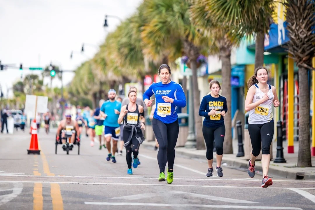 Runners racing down a palm-lined street
